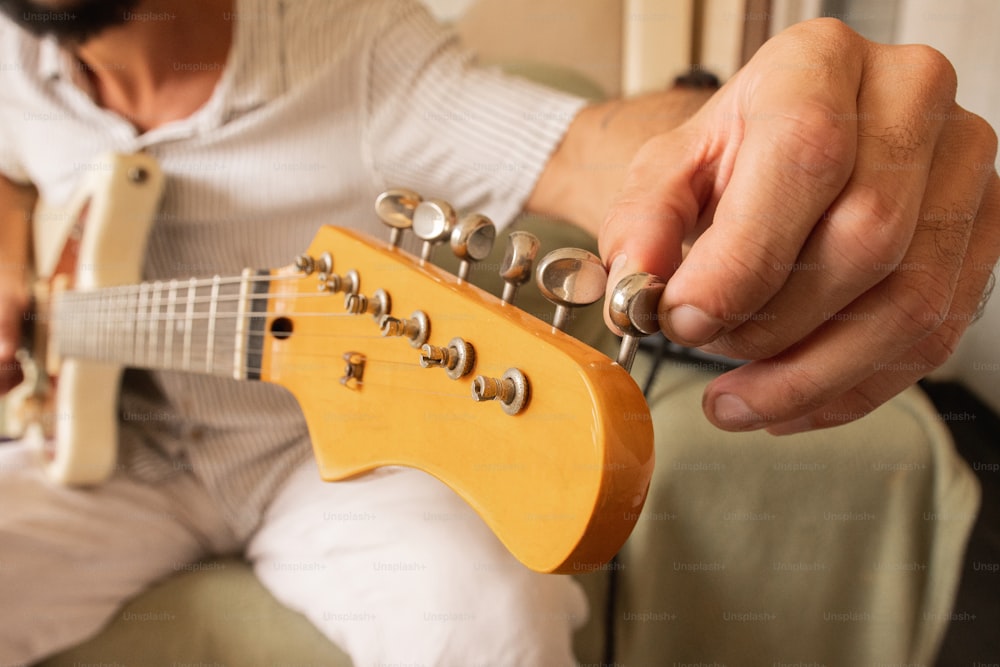 Un uomo che suona una chitarra mentre è seduto su un divano