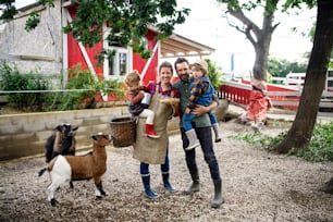 Retrato da família feliz com crianças pequenas em pé na fazenda, segurando a cesta com ovos.