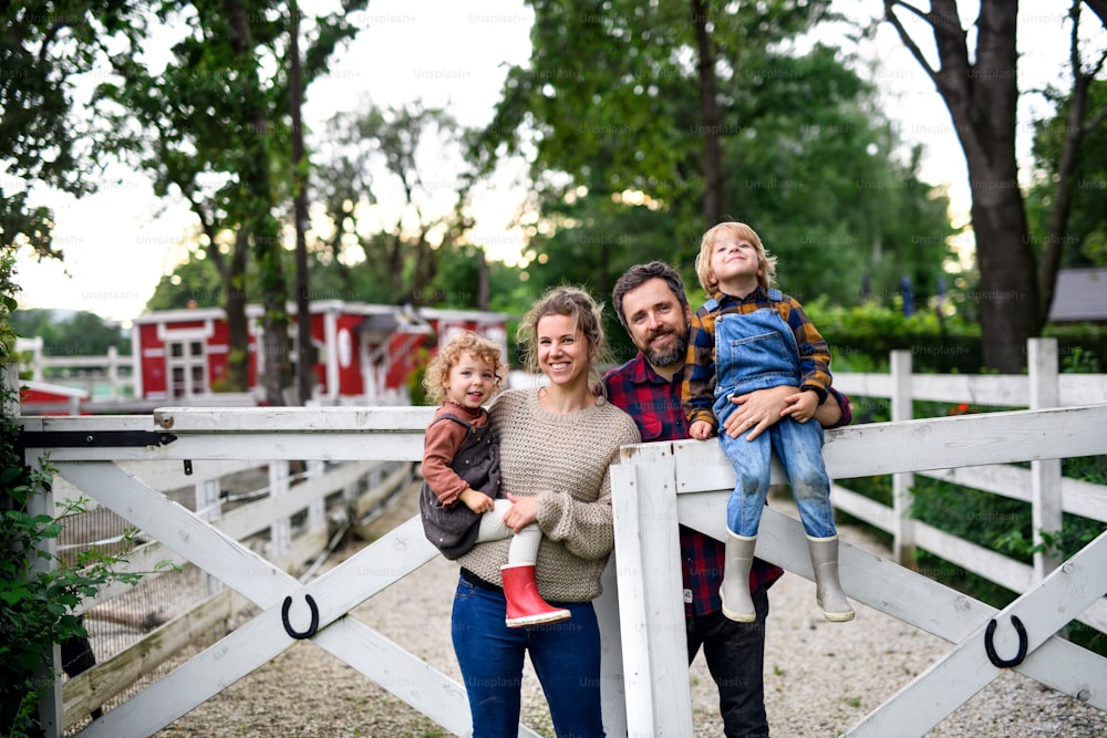 Portrait d’une famille heureuse avec de jeunes enfants debout à la ferme.