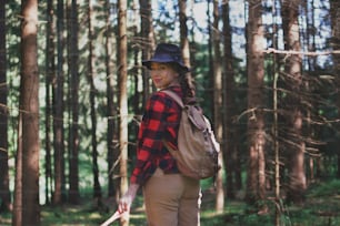 Young woman on a walk outdoors in forest in summer nature, looking back.