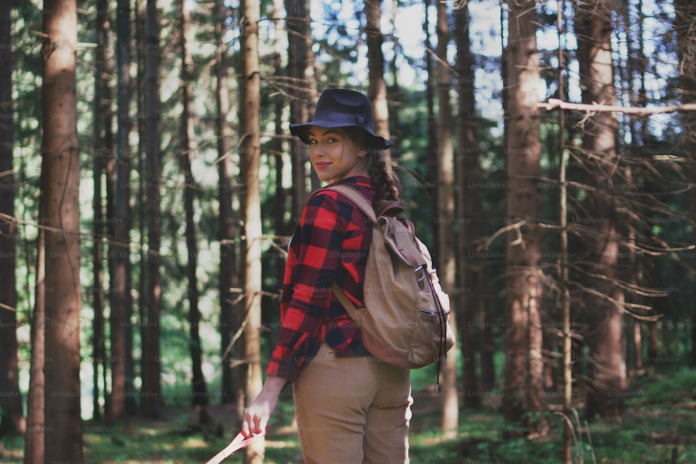 Mujer joven en un paseo al aire libre en el bosque en la naturaleza del verano, mirando hacia atrás.