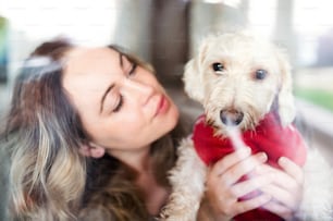 Front view of young woman relaxing indoors at home with pet dog. Shot through glass.