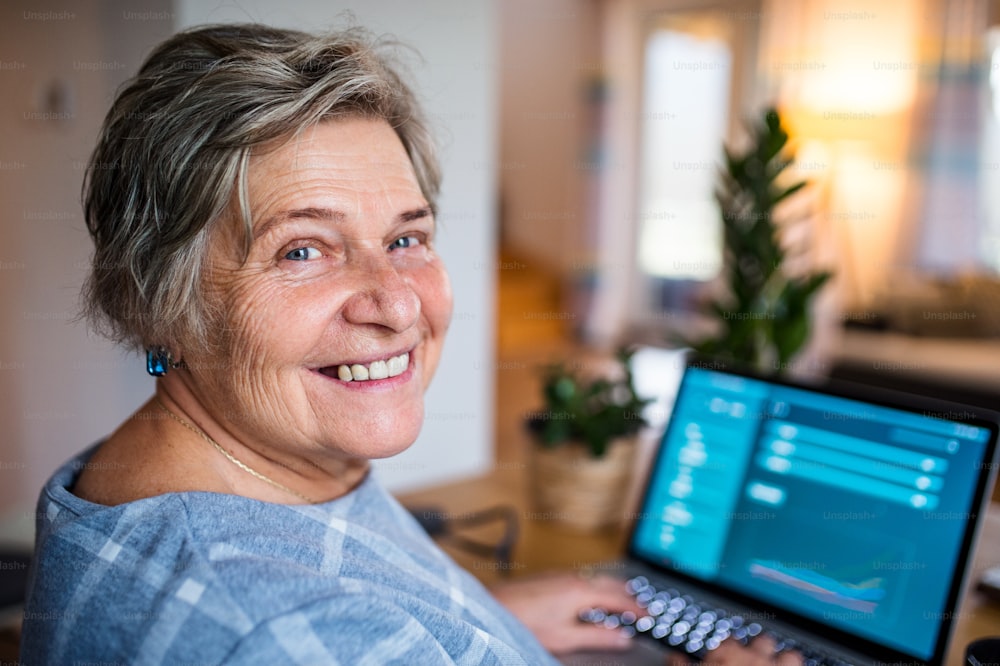 Cheerful senior woman with pet dog and laptop working in home office.