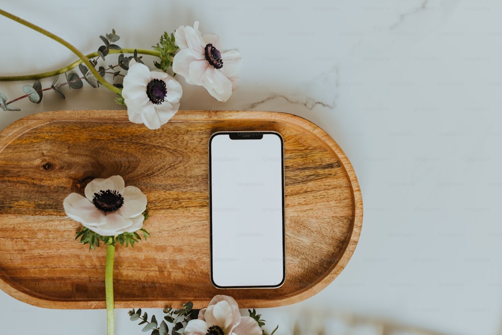 a wooden tray with flowers and a cell phone on it