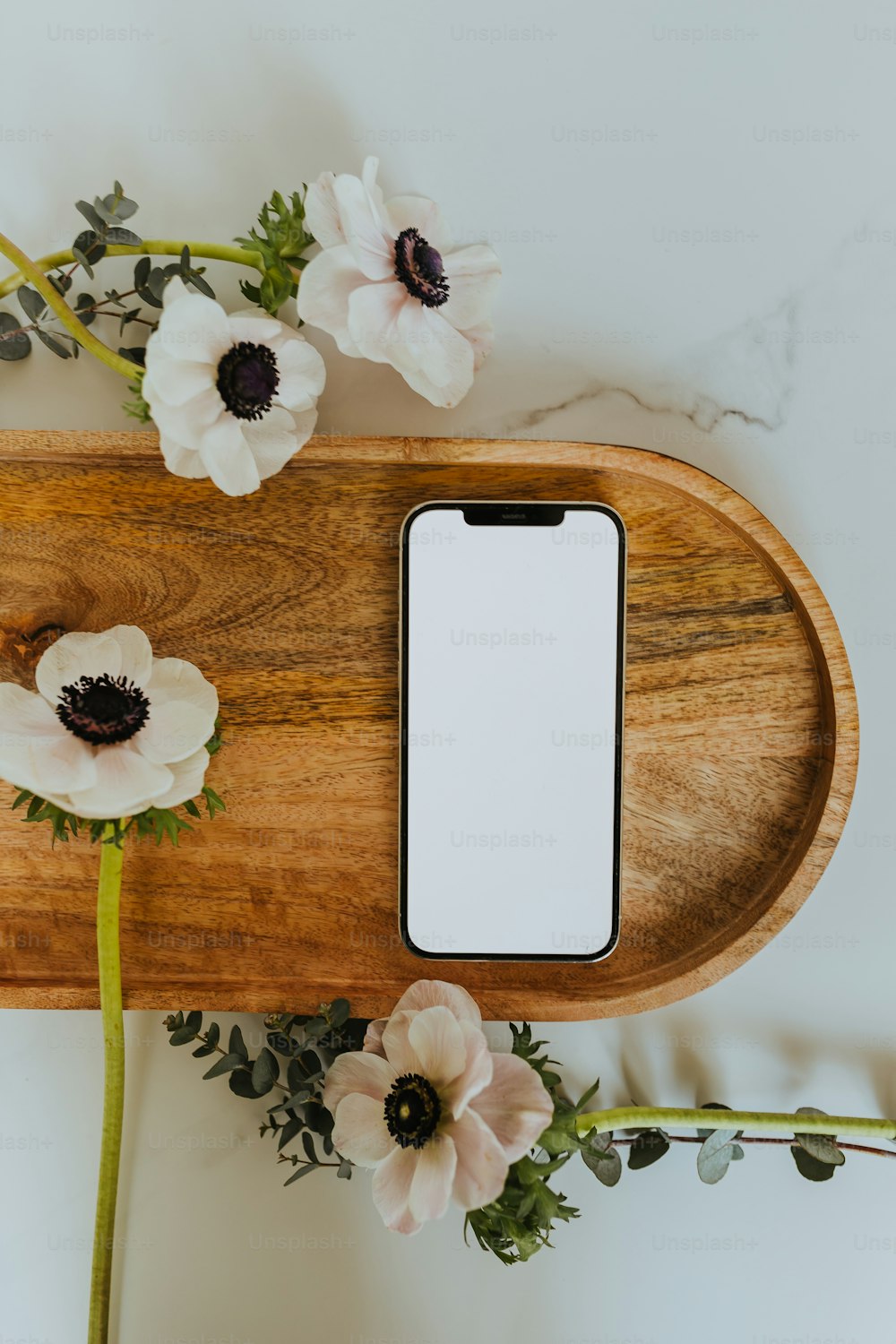 a wooden tray with flowers and a cell phone on it