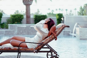 Una mujer acostada en un sillón junto a una piscina