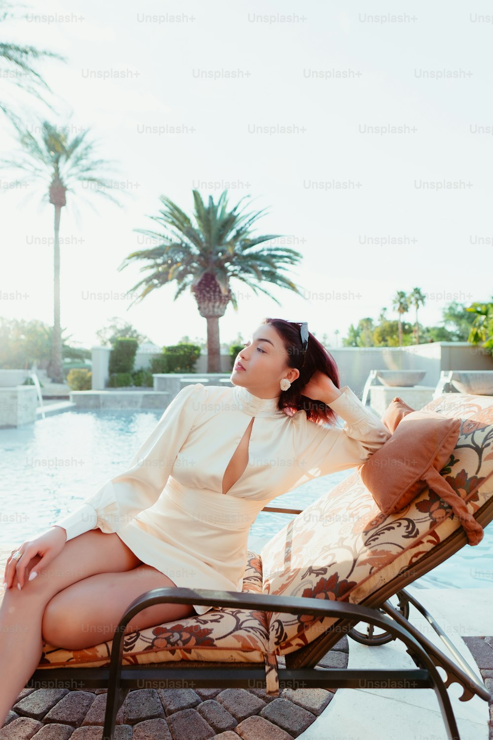 a woman sitting on a lounge chair next to a pool