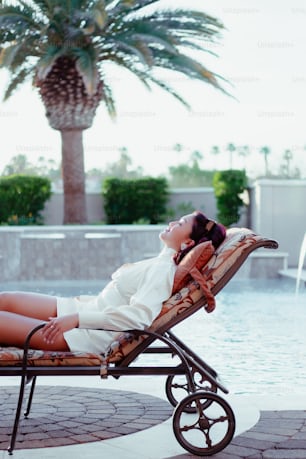 a woman laying on a chaise lounge next to a pool