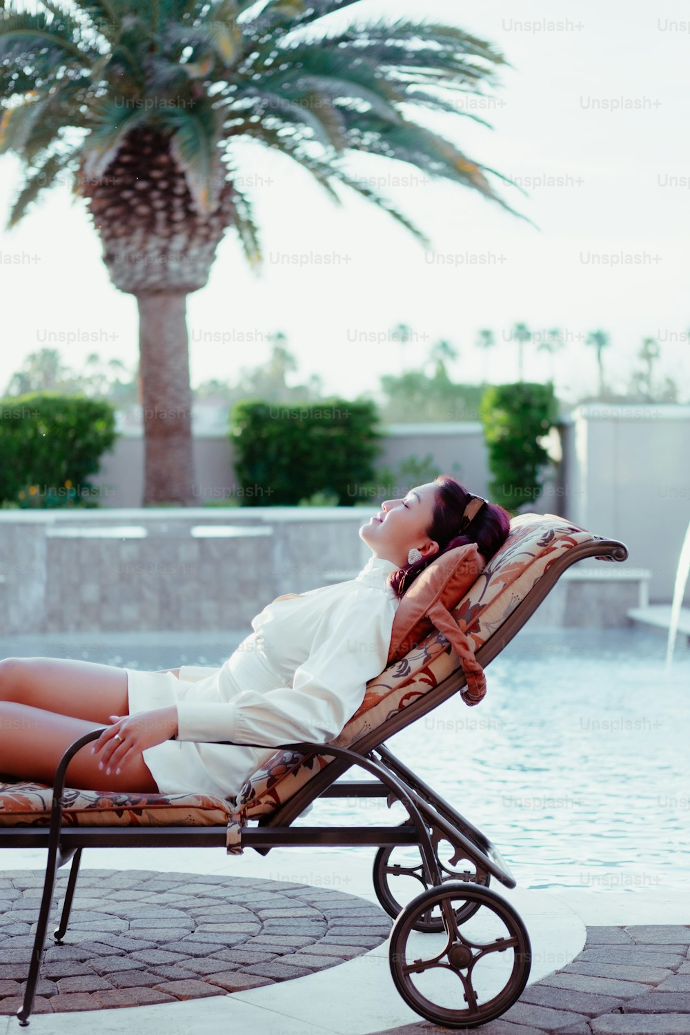 a woman laying on a chaise lounge next to a pool