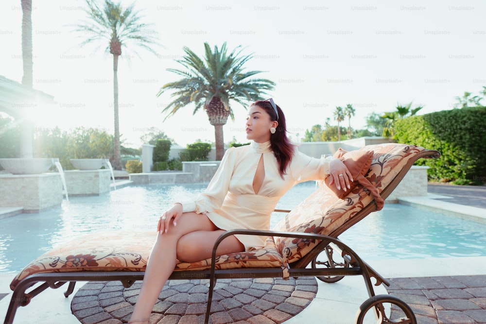 a woman sitting on a bench next to a pool