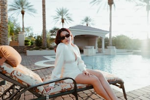 a woman sitting on top of a chair next to a pool