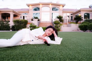 a woman laying on the grass in front of a house