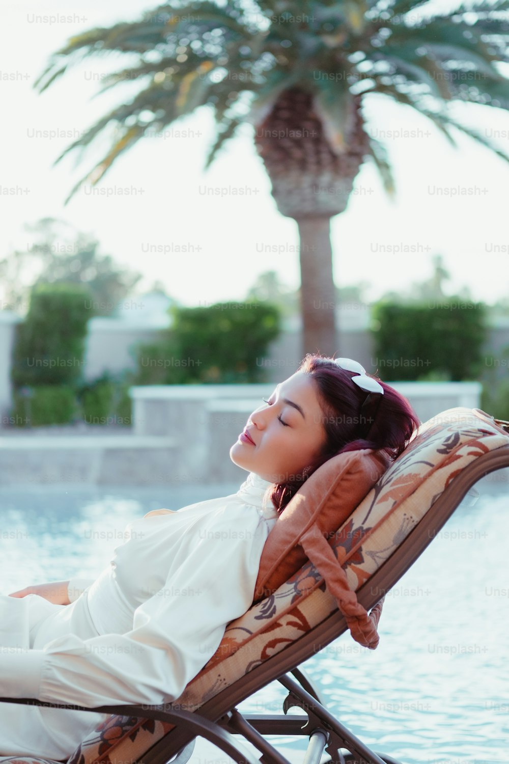 uma mulher deitada em cima de uma cadeira de praia ao lado de uma piscina
