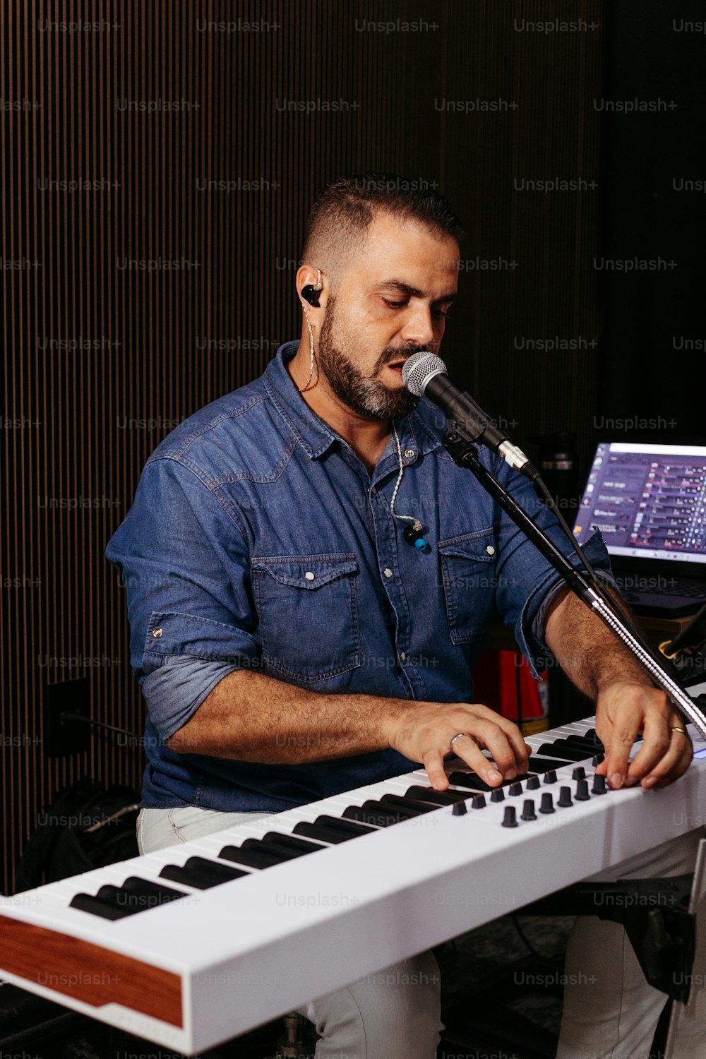 Un uomo seduto a una tastiera con un microfono