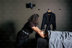 a woman in a black shirt is putting a jacket on a hanger