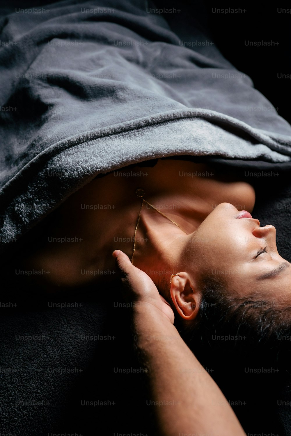 a man laying on top of a bed under a blanket