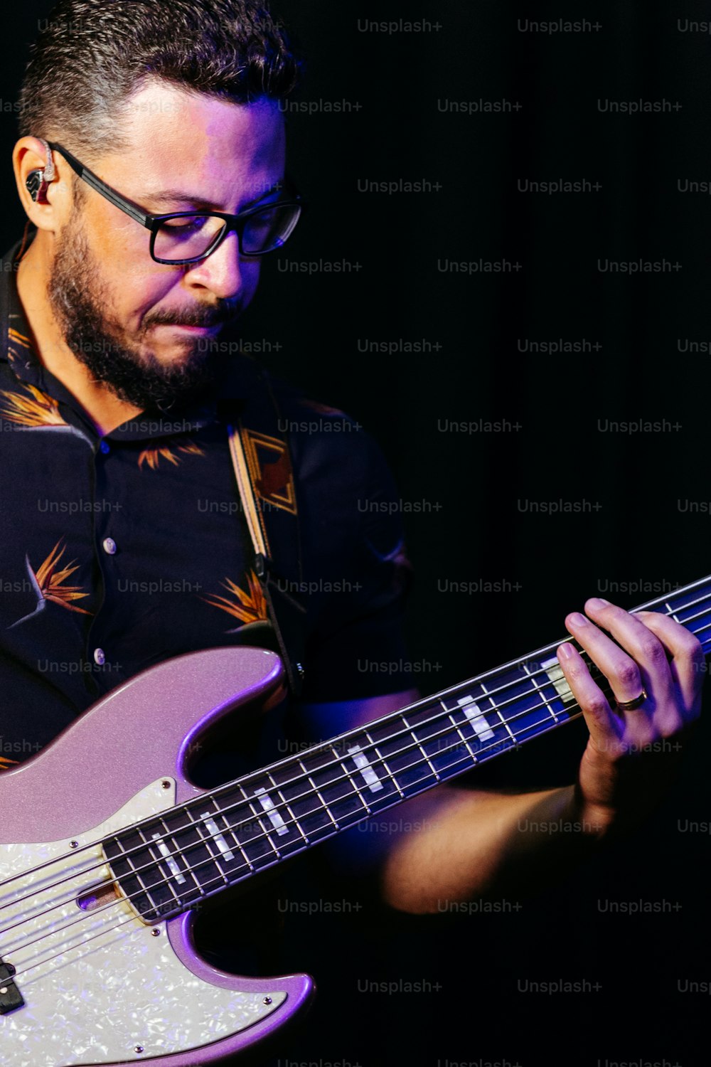 a man with glasses playing a bass guitar
