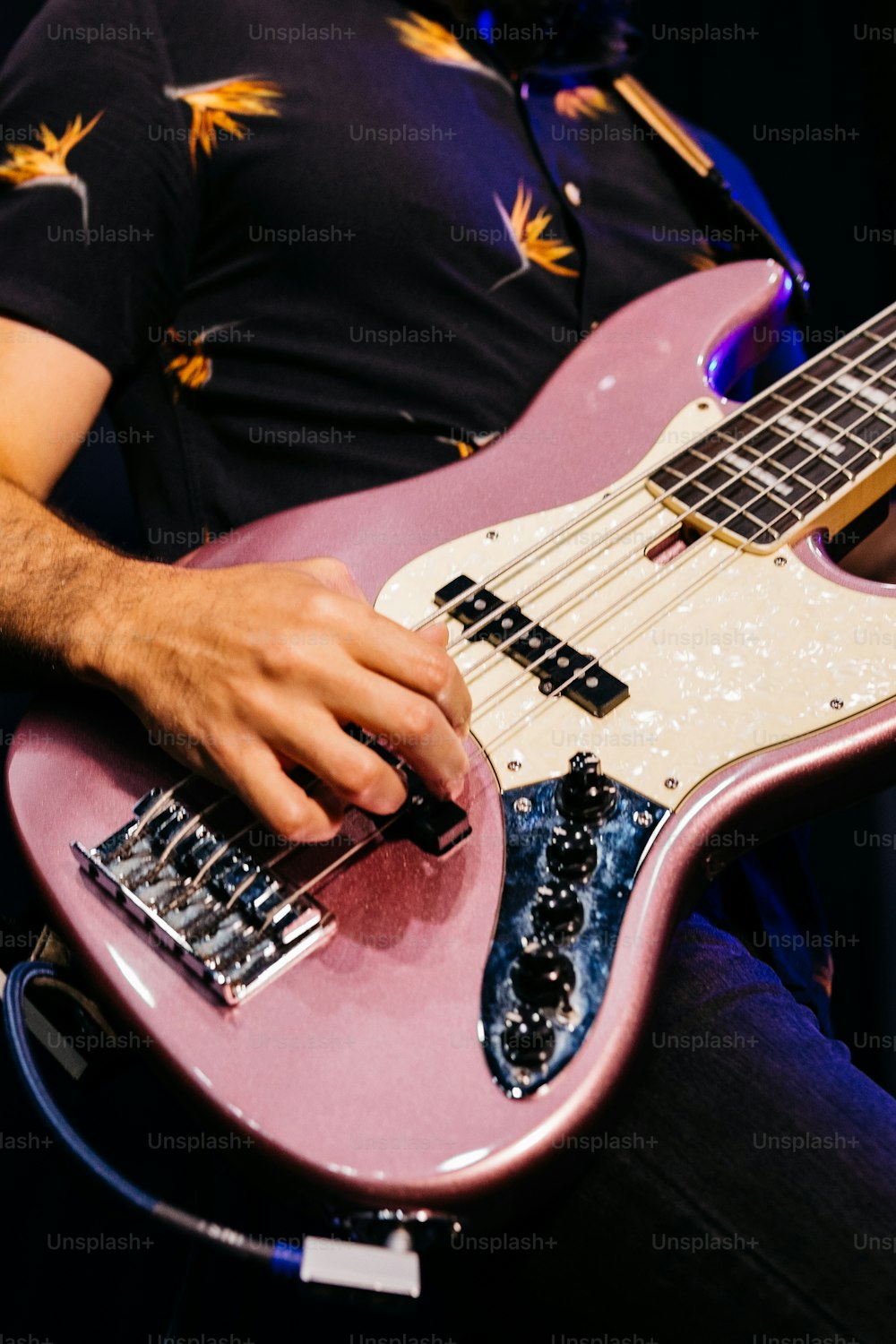 Un hombre tocando una guitarra eléctrica rosa