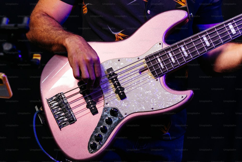 한 남자가 분홍색 베이스 기타를 연주하고 있다