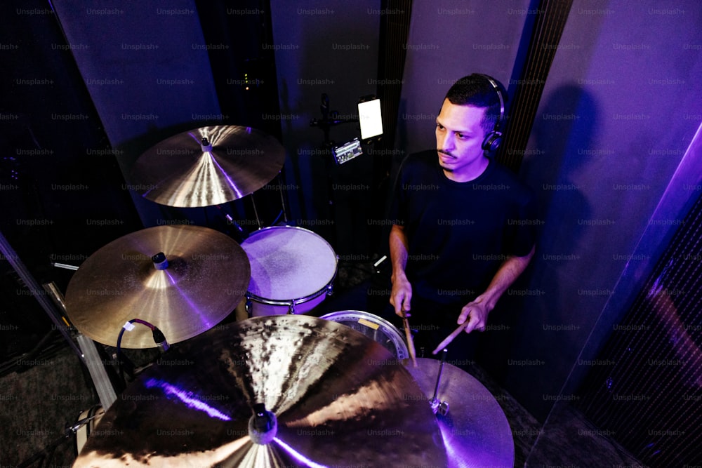 한 남자가 녹음실에서 드럼을 치고 있다