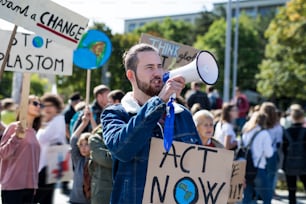 Um homem com cartazes e amplificador sobre a greve global pelas mudanças climáticas, gritando.