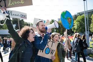 Des gens avec des pancartes et un amplificateur sur une grève mondiale pour le changement climatique, criant.
