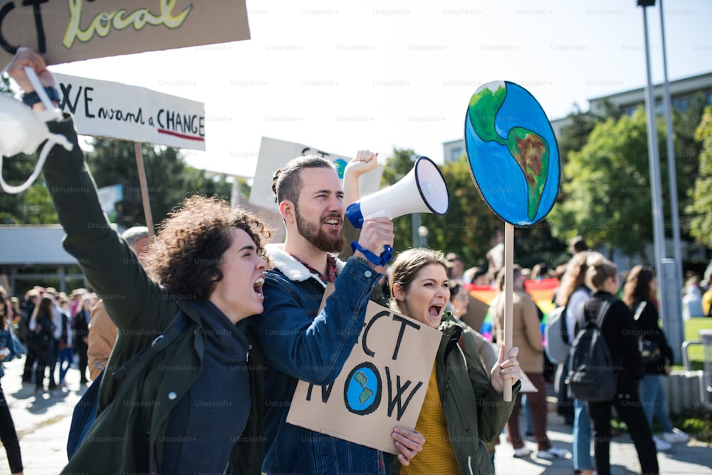 Persone con cartelli e amplificatori su uno sciopero globale per il cambiamento climatico, gridando.