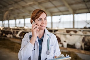 Uma mulher médica veterinária com smartphone trabalhando na fazenda diário, indústria agrícola.