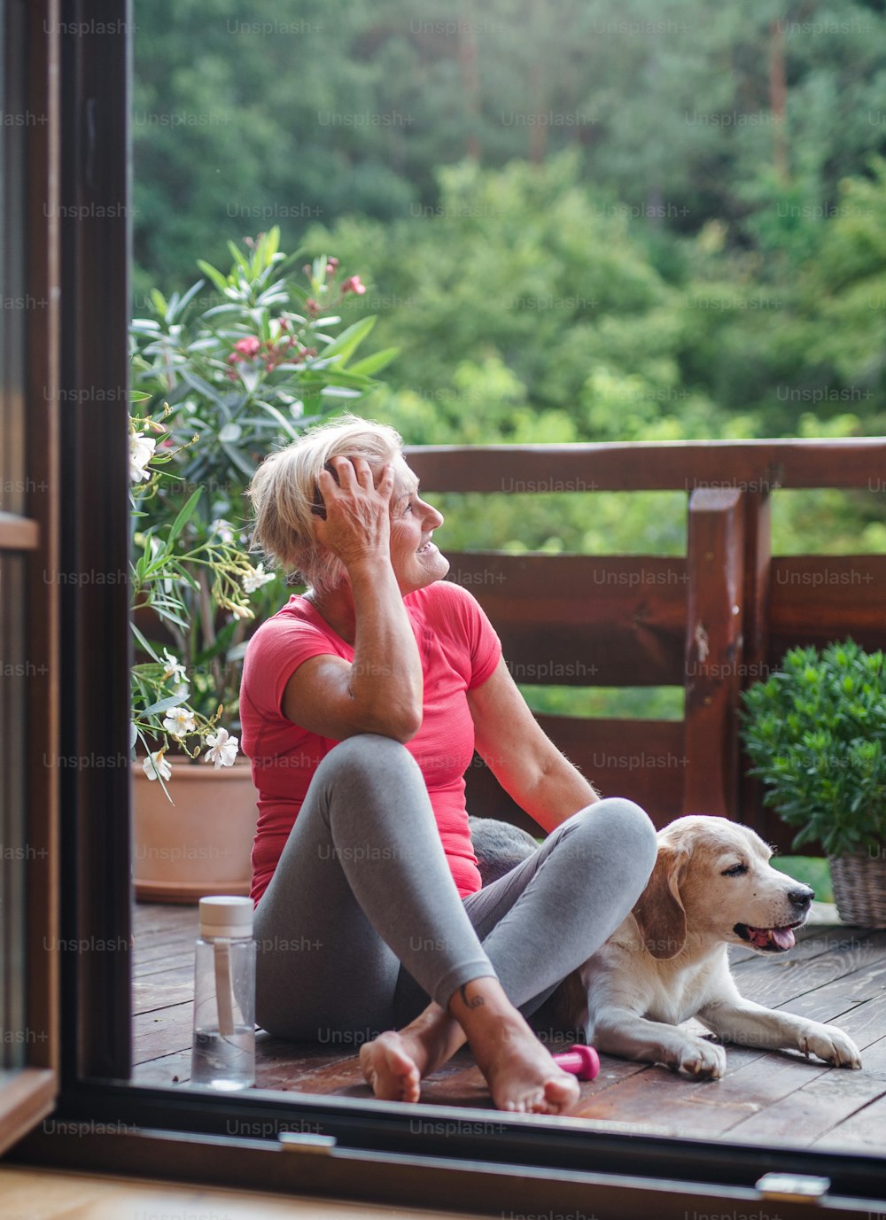 A senior woman with dog outdoors on a terrace in summer, resting after exercise.