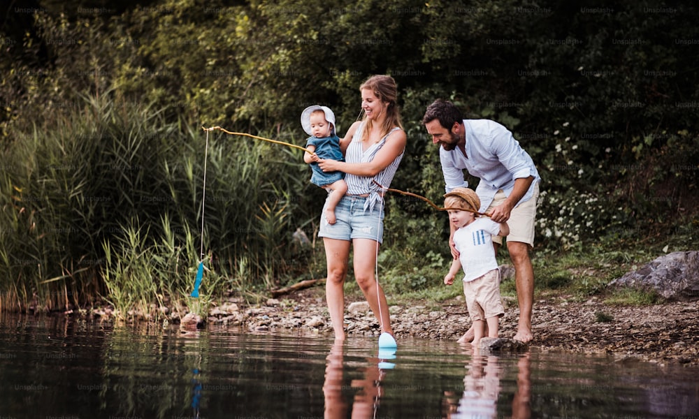 Una giovane famiglia con due bambini piccoli che trascorrono del tempo all'aperto vicino al fiume in estate.