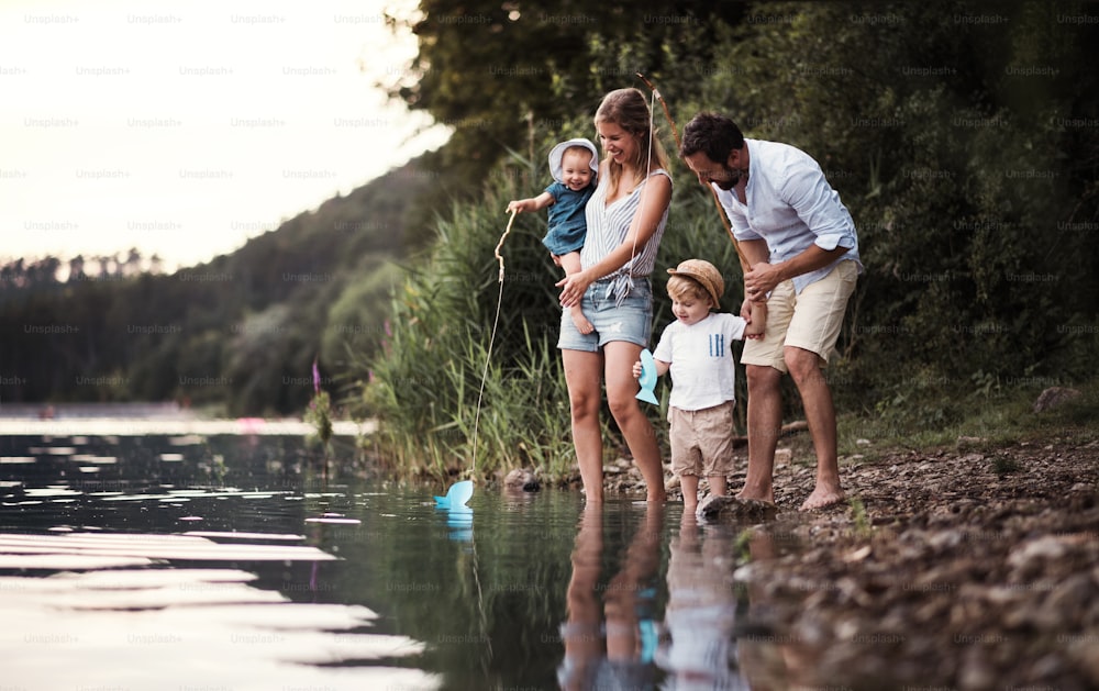 Una giovane famiglia con due bambini piccoli che trascorrono del tempo all'aperto vicino al fiume in estate.