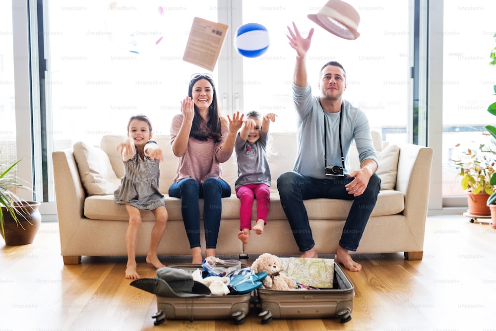Retrato de uma jovem família feliz com duas crianças fazendo as malas para férias em casa.