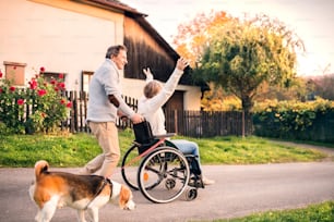 개와 함께 산책하는 노부부. 마을 길에서 휠체어를 탄 여성을 밀고 있는 노인.