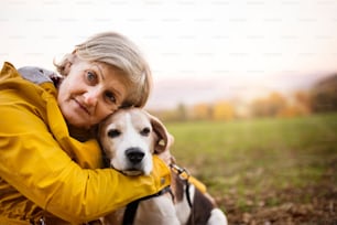 Active senior woman with dog on a walk in a beautiful autumn nature.