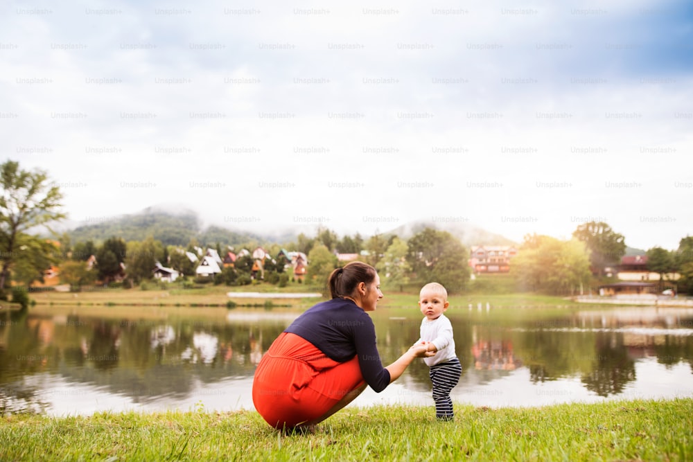 Cute little boy making first steps in nature. mother and son spending time in nature. Summer time.