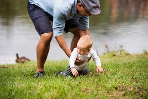 Father and little boy spending time together outside in green nature.