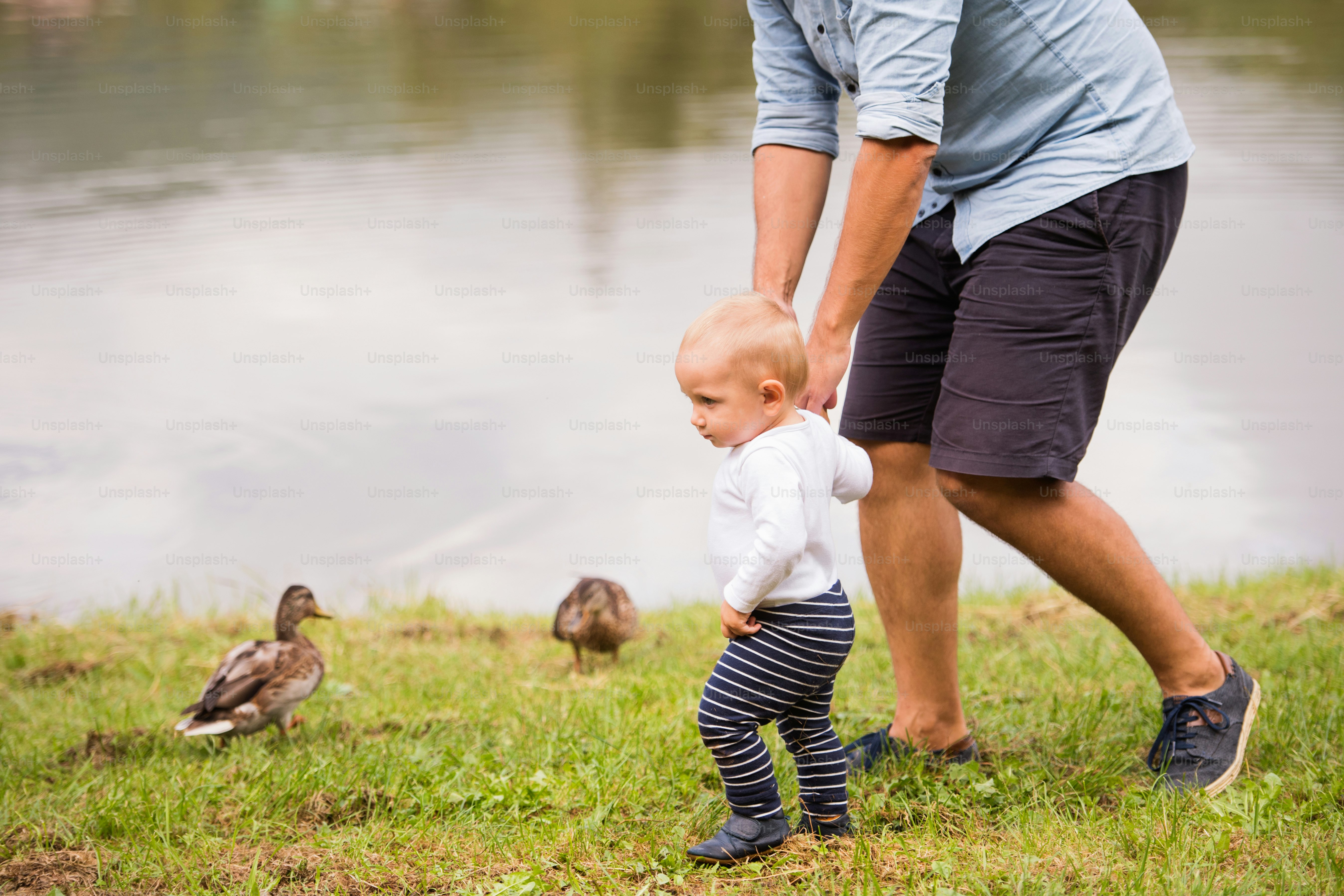 Unrecognizable father and the son spending time together outside in green nature.