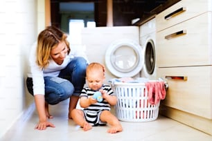 Junge Mutter mit einem kleinen Sohn bei der Hausarbeit. Schöne Frau und kleiner Junge, die Wäsche waschen.