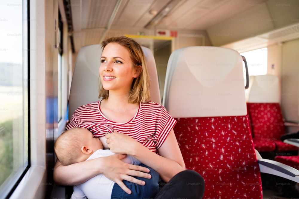 Madre joven que viaja con un bebé en tren. Viaje en tren de una hermosa mujer y su hijo.