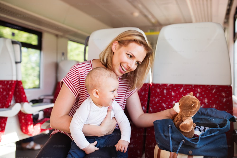 Madre joven que viaja con un bebé en tren. Viaje en tren de una hermosa mujer y su hijo.