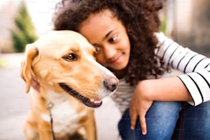 Beautiful african american girl with curl hair, walking outside with her dog.