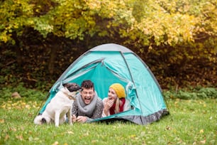 テントに横たわり、秋の自然の中でキャンプをする美しい若い夫婦