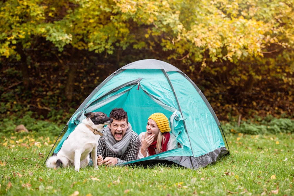 Beautiful young couple lying in tent, camping in autumn nature