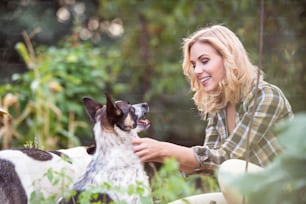 Beautiful blond woman with her dogs in green garden