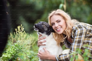 Beautiful blond woman with her dog in green garden