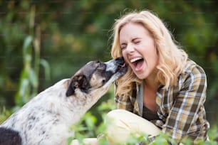 Schöne blonde Frau mit ihrem Hund im grünen Garten