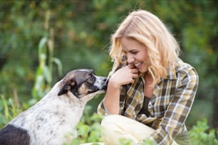 Hermosa mujer rubia con su perro en el jardín verde