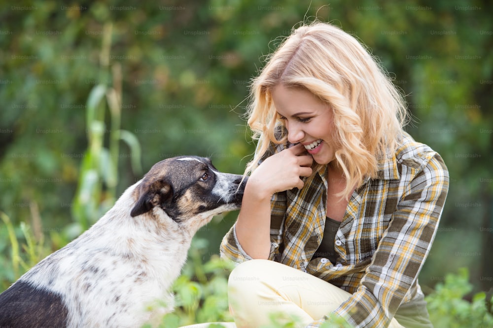 Beautiful blond woman with her dog in green garden