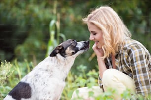 Hermosa mujer rubia con su perro en el jardín verde