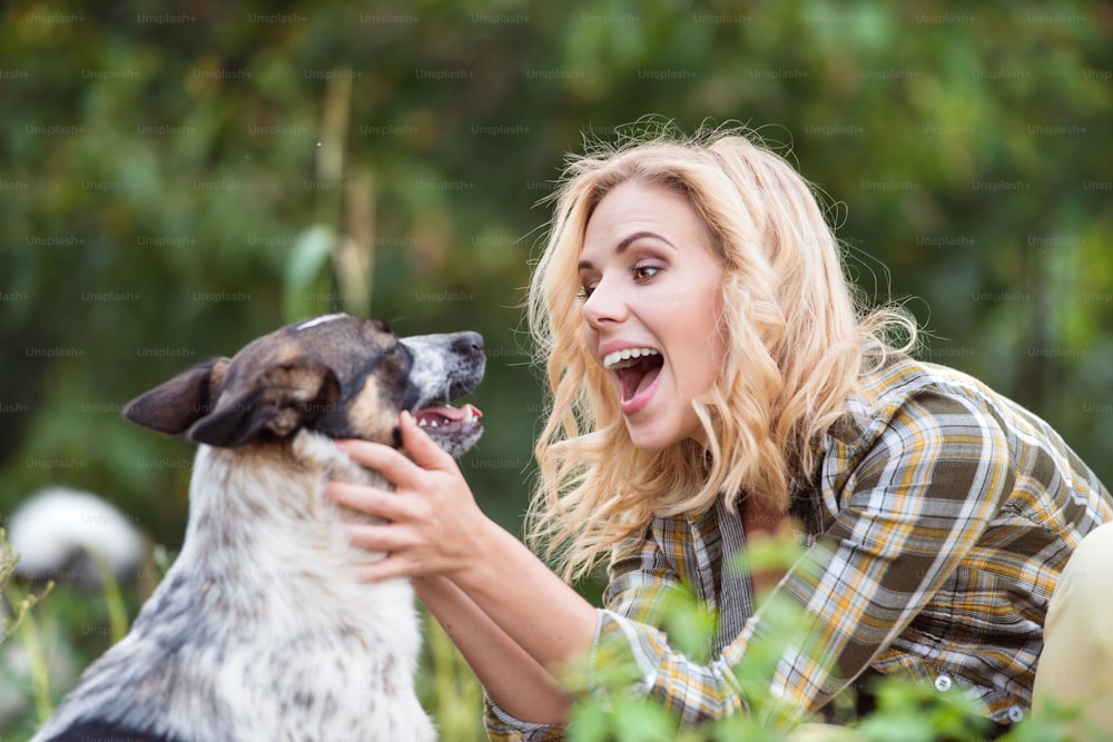 Beautiful blond woman with her dog in green garden